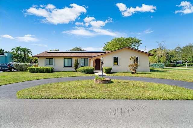 ranch-style house with solar panels and a front lawn