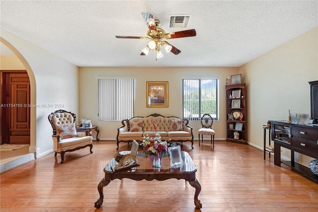 living room with a textured ceiling, light hardwood / wood-style floors, and ceiling fan