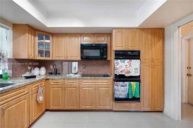 kitchen featuring light brown cabinets, black appliances, decorative backsplash, light stone countertops, and light tile patterned floors