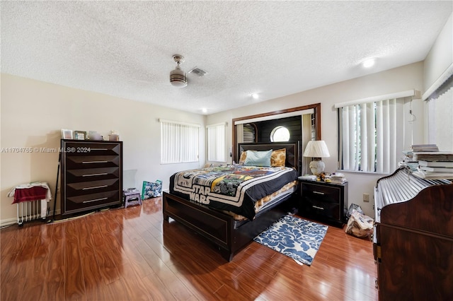 bedroom featuring hardwood / wood-style floors, a textured ceiling, and ceiling fan