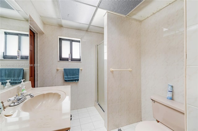 bathroom with a shower with door, sink, tile patterned flooring, toilet, and tile walls