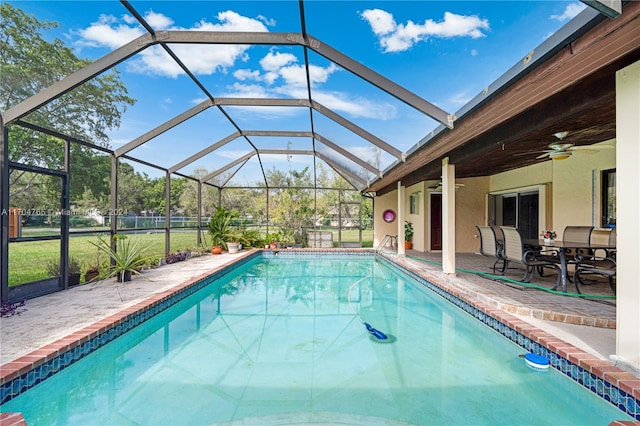 view of pool featuring a patio, glass enclosure, and ceiling fan