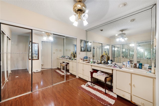 bathroom featuring vanity, wood-type flooring, a textured ceiling, and ceiling fan