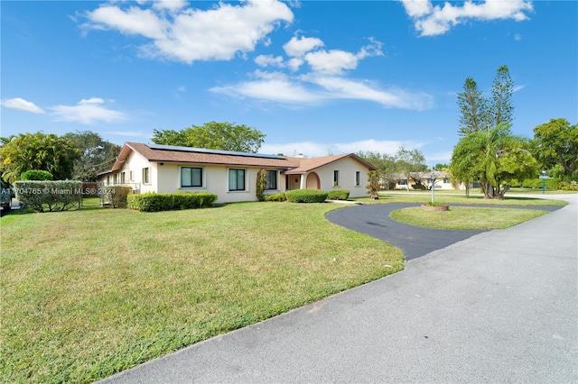 ranch-style house featuring solar panels and a front yard