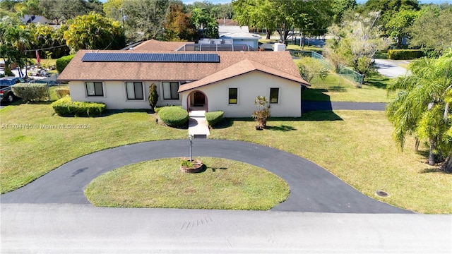 view of front facade featuring solar panels and a front lawn