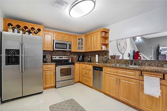 kitchen featuring light tile patterned flooring, sink, tasteful backsplash, dark stone countertops, and stainless steel appliances