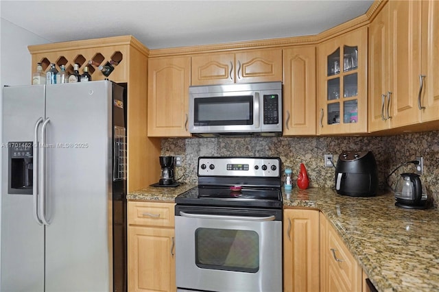 kitchen with stainless steel appliances, light brown cabinets, light stone counters, and decorative backsplash