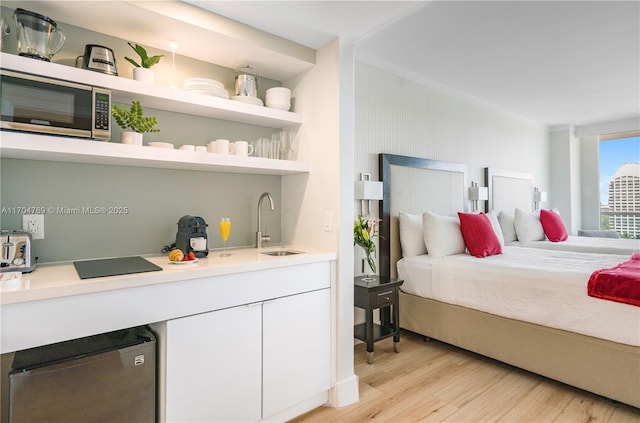 bedroom with stainless steel refrigerator, sink, and light wood-type flooring