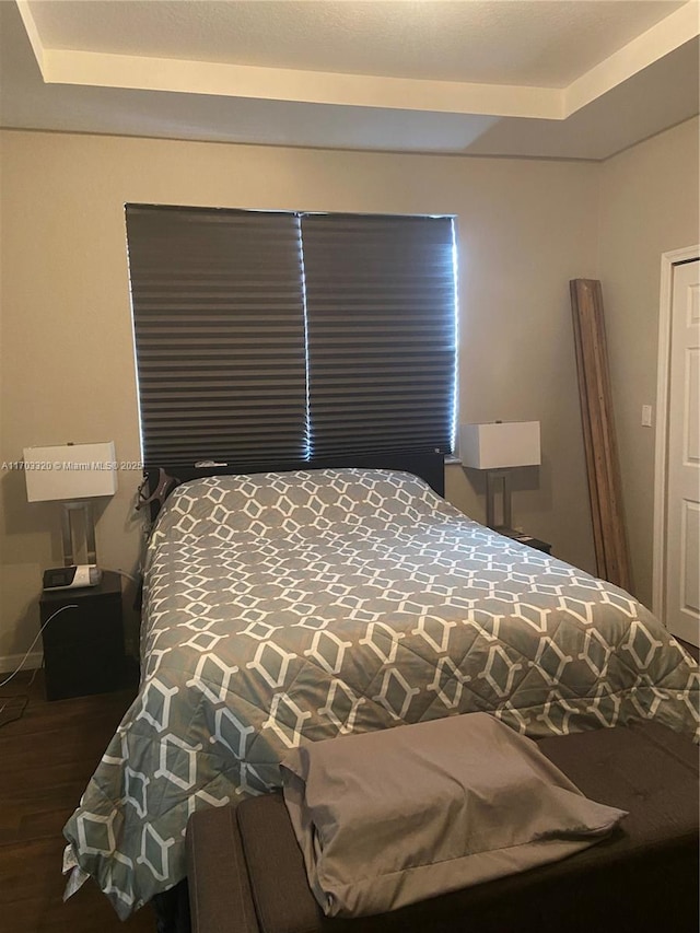 bedroom with wood-type flooring and a raised ceiling