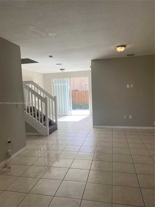 empty room with light tile patterned floors and a textured ceiling