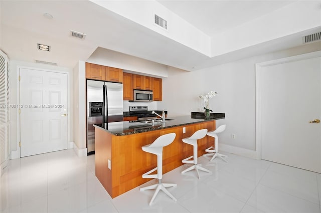 kitchen featuring a breakfast bar, sink, appliances with stainless steel finishes, light tile patterned flooring, and kitchen peninsula