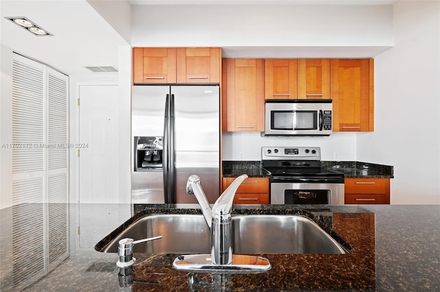 kitchen featuring dark stone countertops, sink, and stainless steel appliances