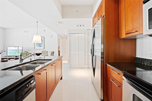 kitchen with decorative light fixtures, dark stone countertops, sink, and appliances with stainless steel finishes