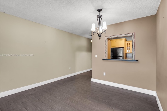 empty room featuring a textured ceiling and a notable chandelier