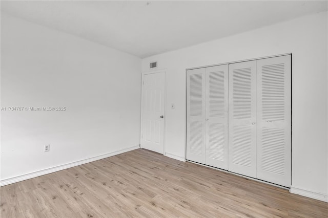 unfurnished bedroom with light wood-type flooring and a closet