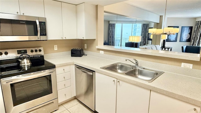 kitchen with sink, white cabinets, light tile patterned floors, and appliances with stainless steel finishes