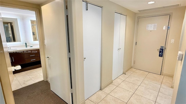 hallway featuring light tile patterned flooring and sink