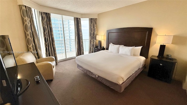 bedroom with access to outside, dark carpet, and a textured ceiling