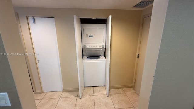 laundry room with light tile patterned flooring and stacked washing maching and dryer