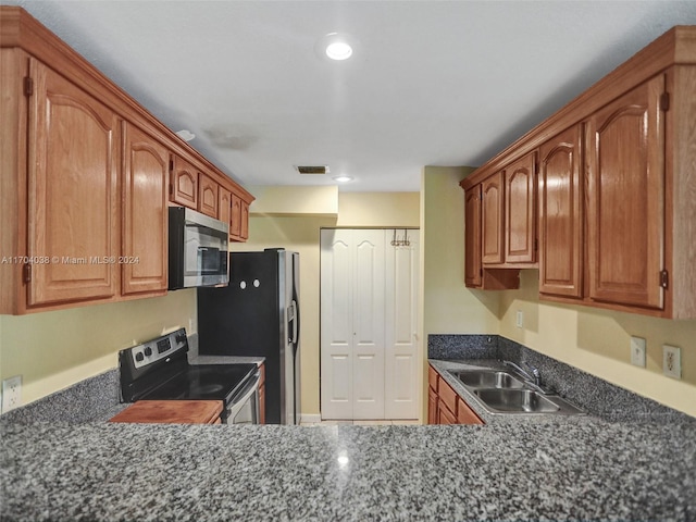 kitchen with dark stone countertops, sink, and stainless steel appliances