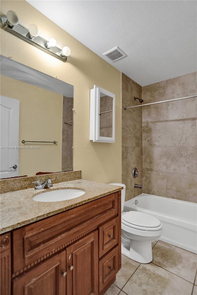 full bathroom with tile patterned flooring, toilet, a textured ceiling, and tiled shower / bath