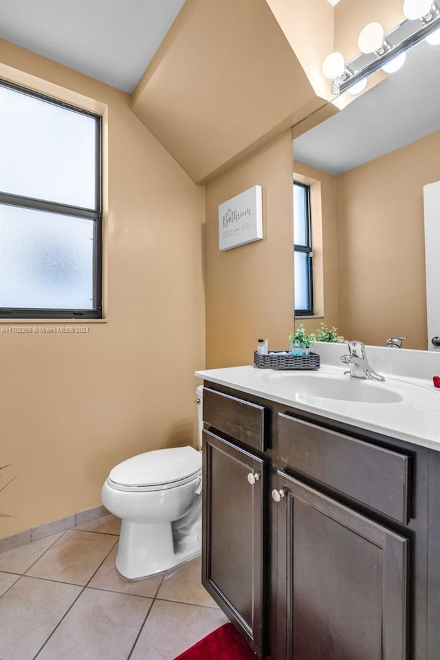 bathroom with toilet, plenty of natural light, vanity, and tile patterned flooring