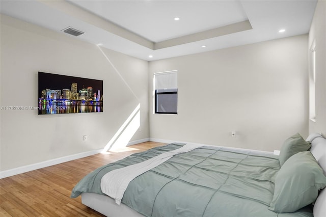 bedroom with a tray ceiling and hardwood / wood-style floors