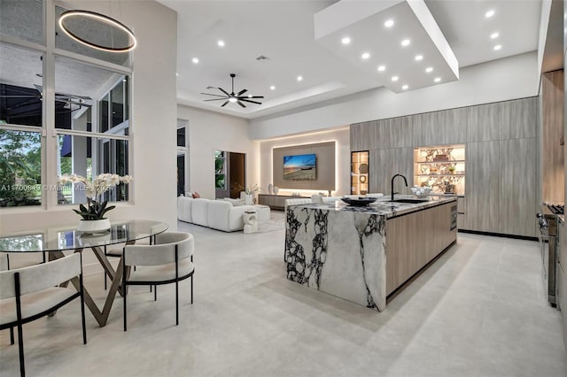 kitchen with a large island with sink, a wealth of natural light, ceiling fan, and dark stone countertops