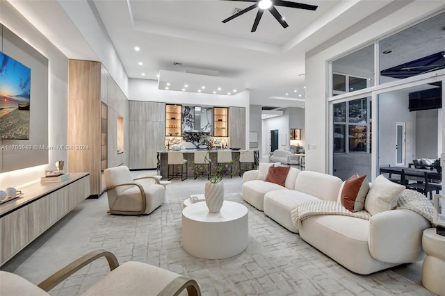 living room with a raised ceiling and ceiling fan