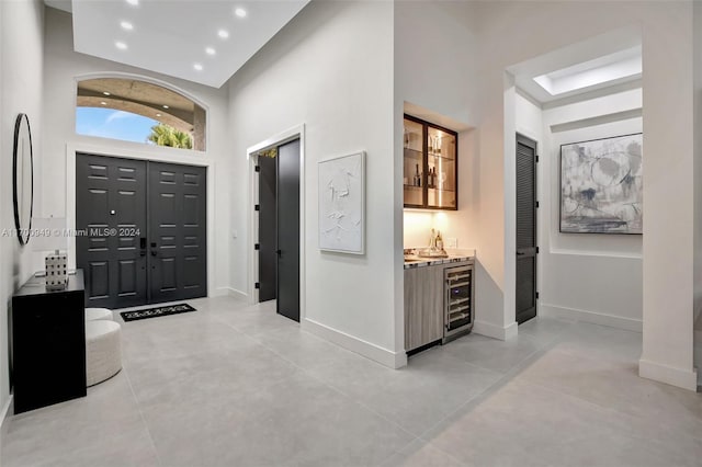 entrance foyer featuring wine cooler, a towering ceiling, and indoor bar