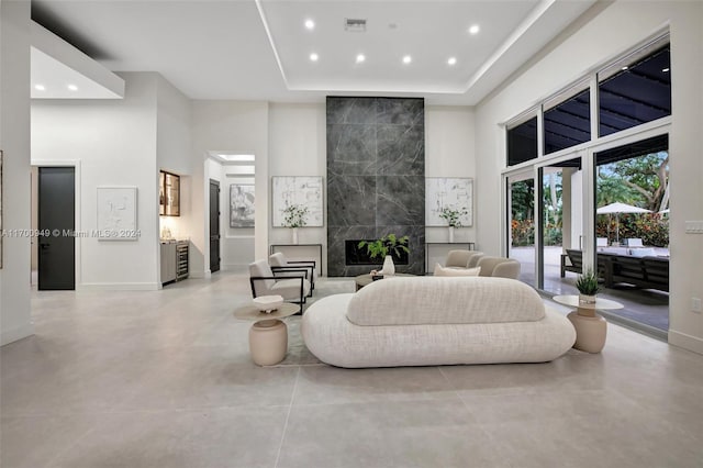 living room with a fireplace, a high ceiling, and a raised ceiling