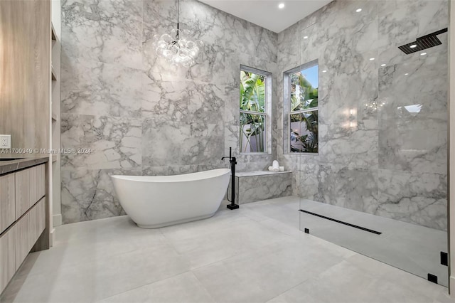 bathroom with a notable chandelier, vanity, separate shower and tub, and tile walls