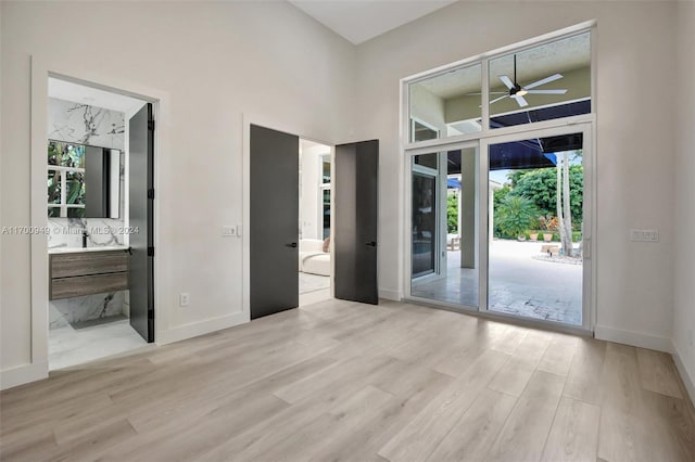 interior space with a high ceiling, light wood-type flooring, plenty of natural light, and ceiling fan