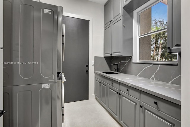 interior space featuring cabinets, stacked washer / dryer, and sink