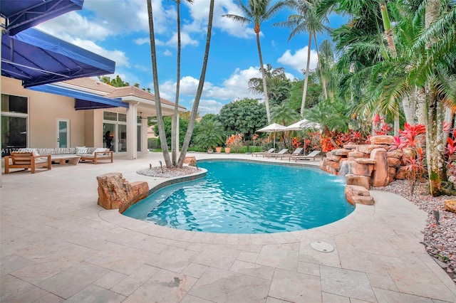 view of swimming pool with pool water feature, an outdoor living space, and a patio area