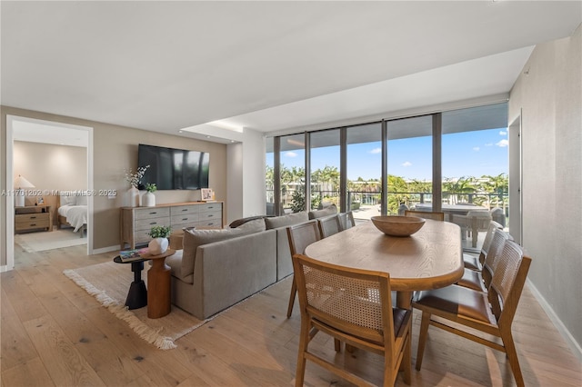 dining area featuring expansive windows, light wood-style flooring, and baseboards