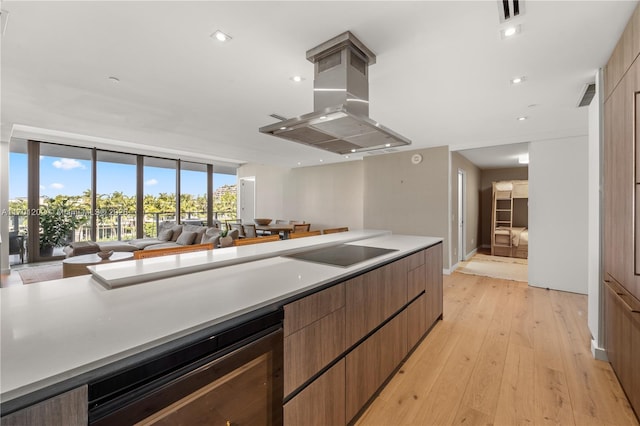 kitchen with beverage cooler, visible vents, island range hood, light wood-style flooring, and black electric stovetop