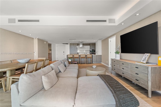 living area with light wood finished floors, visible vents, and recessed lighting