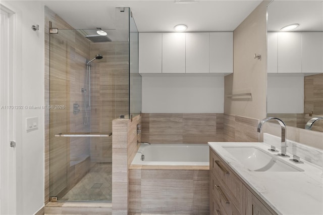 bathroom featuring a garden tub, a shower stall, and vanity