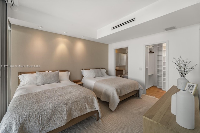 bedroom featuring recessed lighting, a walk in closet, visible vents, and light wood finished floors