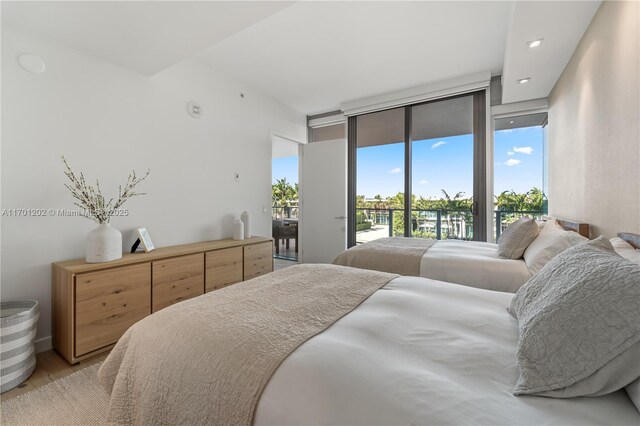 bedroom with access to exterior, a wall of windows, light hardwood / wood-style flooring, and multiple windows