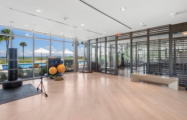 interior space with a wall of windows, recessed lighting, and wood finished floors