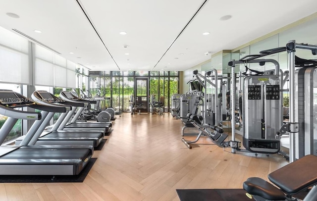 gym with a wall of windows, wood finished floors, and recessed lighting