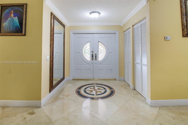 foyer with ornamental molding and a textured ceiling