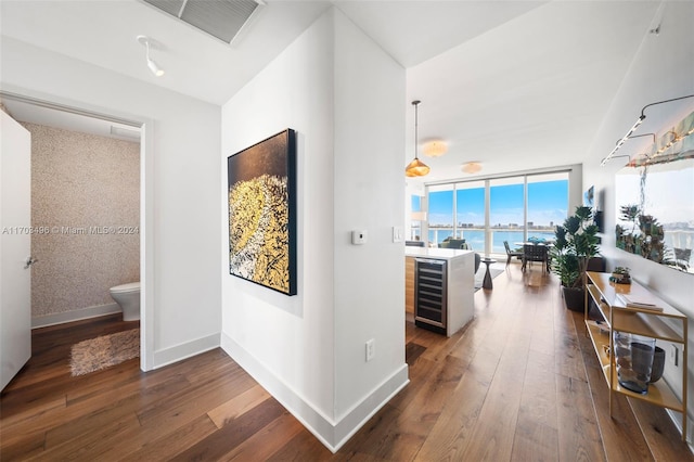 hallway with wine cooler, a water view, and dark wood-type flooring