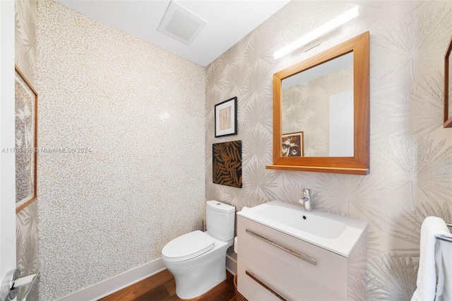 bathroom with vanity, toilet, and wood-type flooring