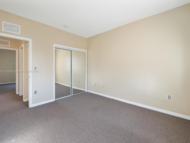 unfurnished bedroom with dark carpet and a closet