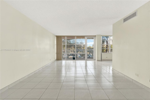 spare room featuring expansive windows, light tile patterned floors, and a textured ceiling