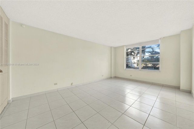 spare room featuring light tile patterned floors and a textured ceiling