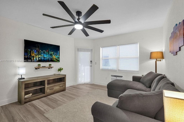 living room featuring light hardwood / wood-style flooring, ceiling fan, and an AC wall unit